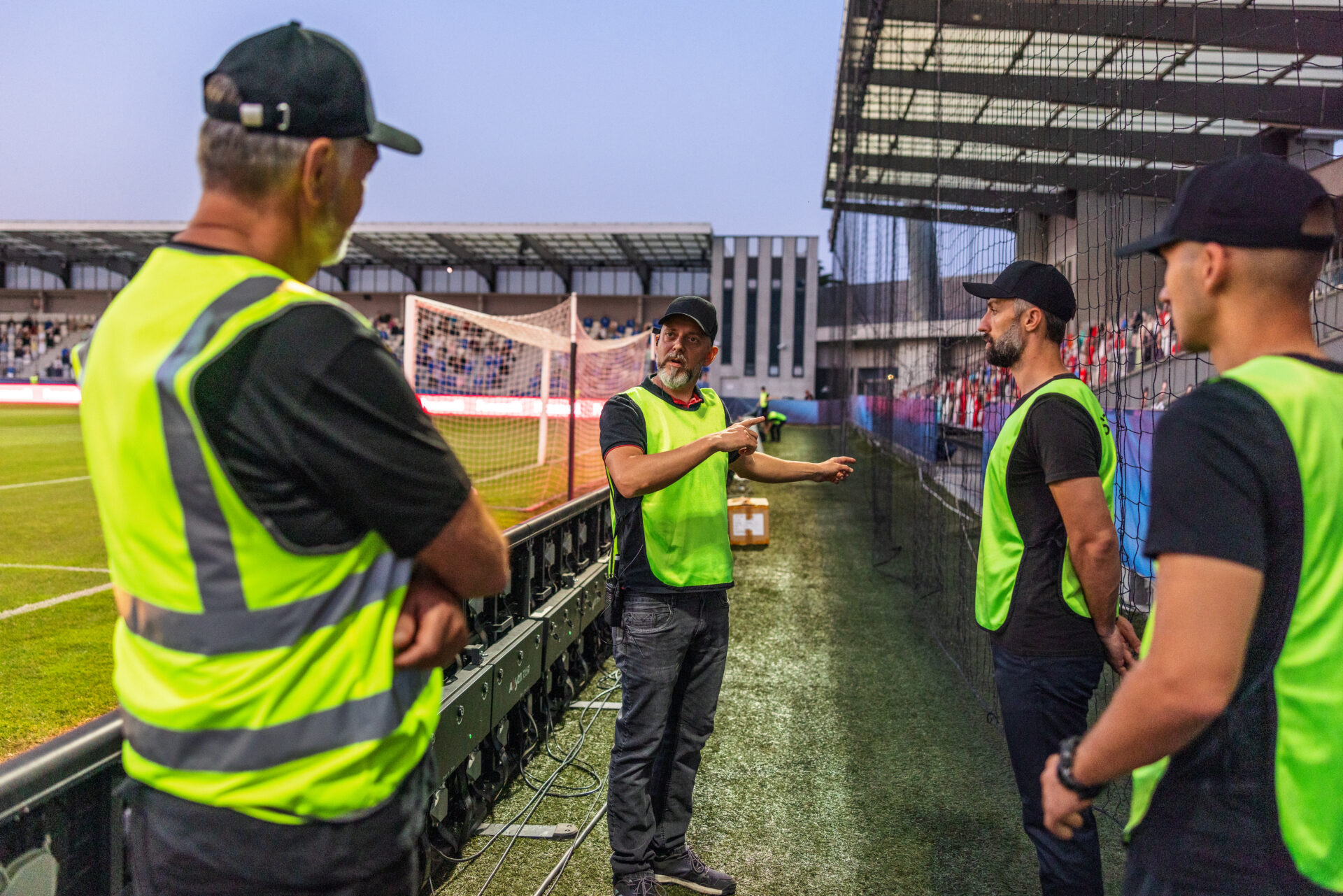 Security team briefing near a soccer field.