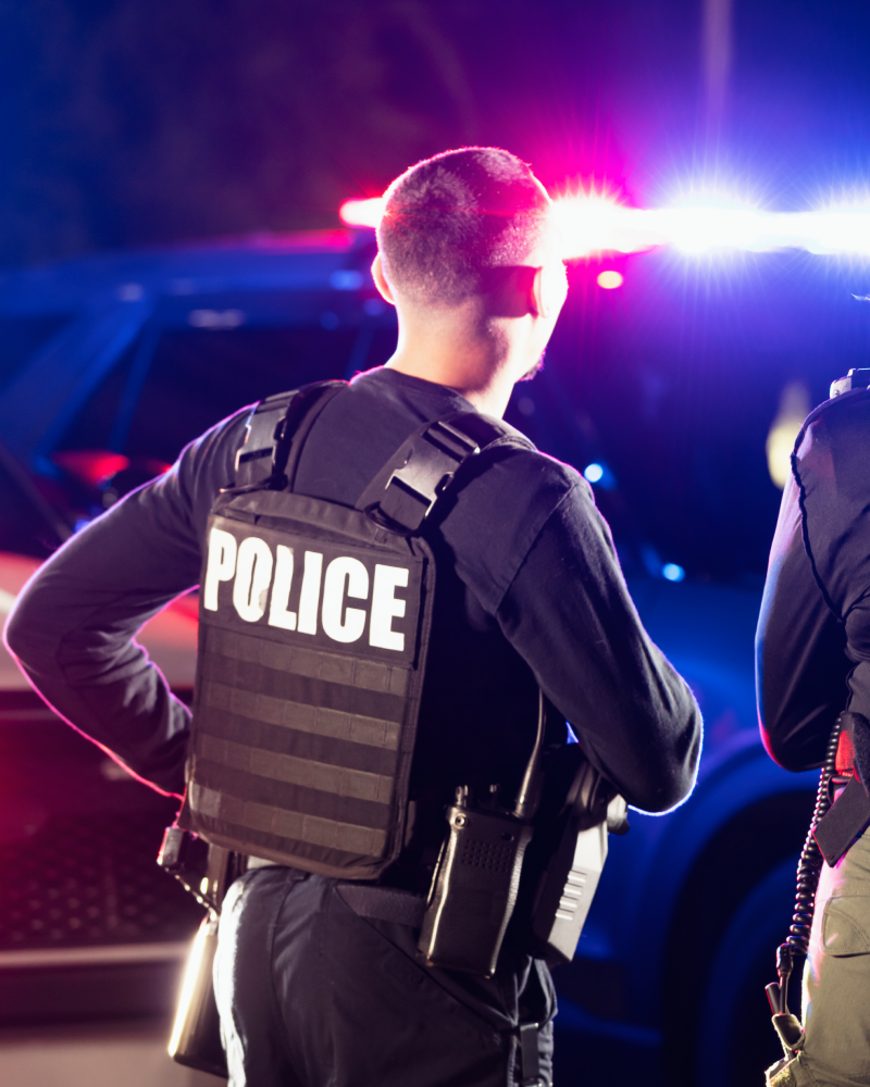 Police officer at night with flashing lights.